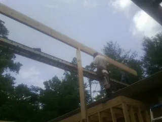 Carpenter setting a ridge beam over a new addition frame — Ice Dam Removal by Roofing Brothers in Newton